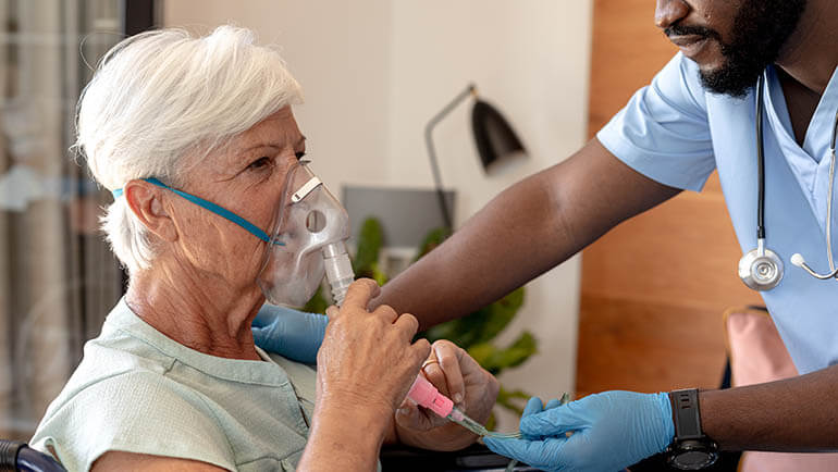 Uma senhora idosa recebendo oxigênio medicinal de um enfermeiro