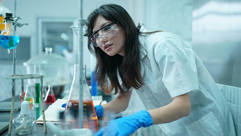 cientista com roupas de proteção coletando amostras e examinando-as durante o experimento no laboratório