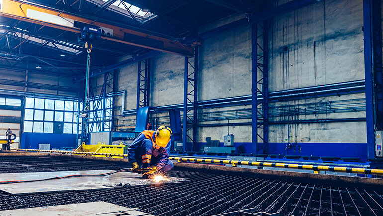 Trabalhador cortando metal, aço com tocha de acetileno em grande fábrica. Indústria pesada, estaleiro